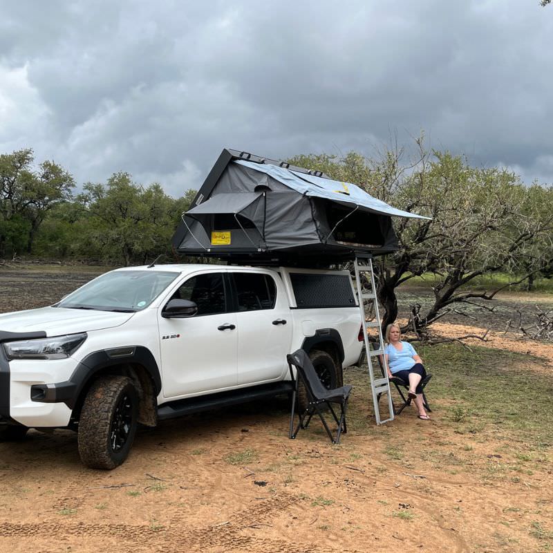 eezi-awn-sword-hard-shell-roof-top-tent-open-front-corner-view-on-vehicle-with-person-in-nature