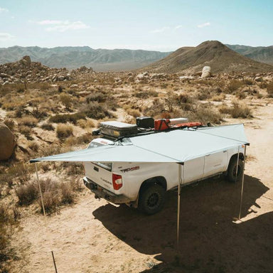 eezi-awn-dragonfly-180-open-beige-top-corner-view-on-toyota-tundra-in-nature