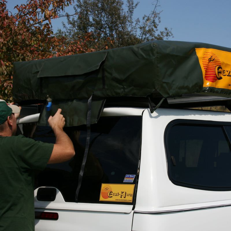 eezi-awn-jazz-soft-shell-roof-top-tent-closed-rear-corner-view-on-vehicle-with-person-in-nature