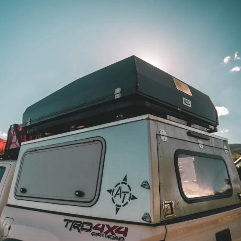 eezi-awn-sabre-hard-shell-roof-top-tent-closed-rear-corner-view-on-vehicle-in-nature