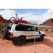 eezi-awn-series-1000-awning-beige-open-side-view-silver-hardcase-on-land-cruiser-beside-kayak-in-terrain