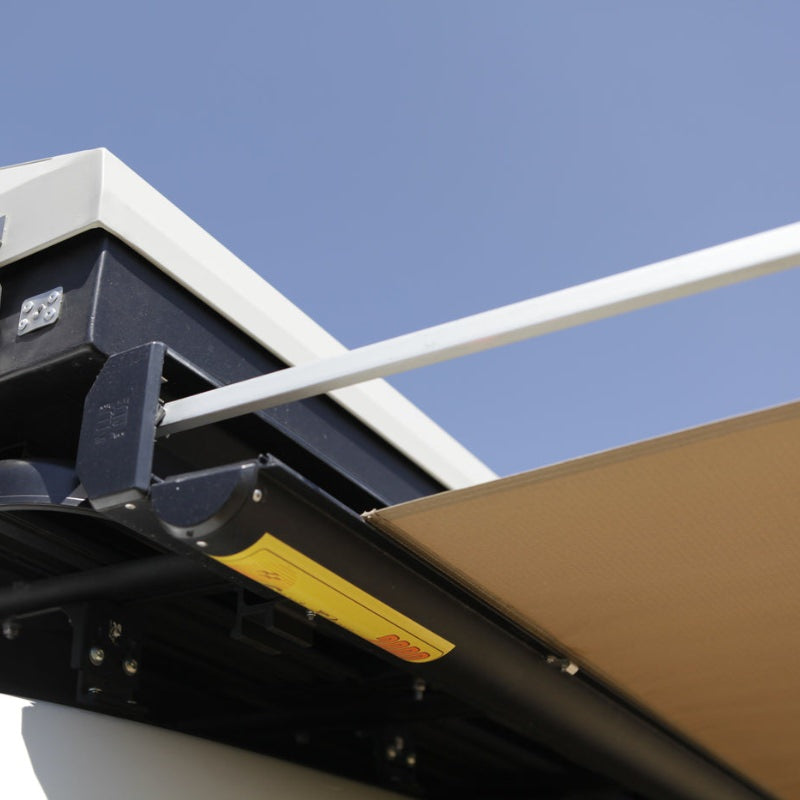 eezi-awn-series-2000-awning-beige-open-close-up-view-black-hardcase-with-brand-logo-beside-hard-shell-tent-on-vehicle-in-nature