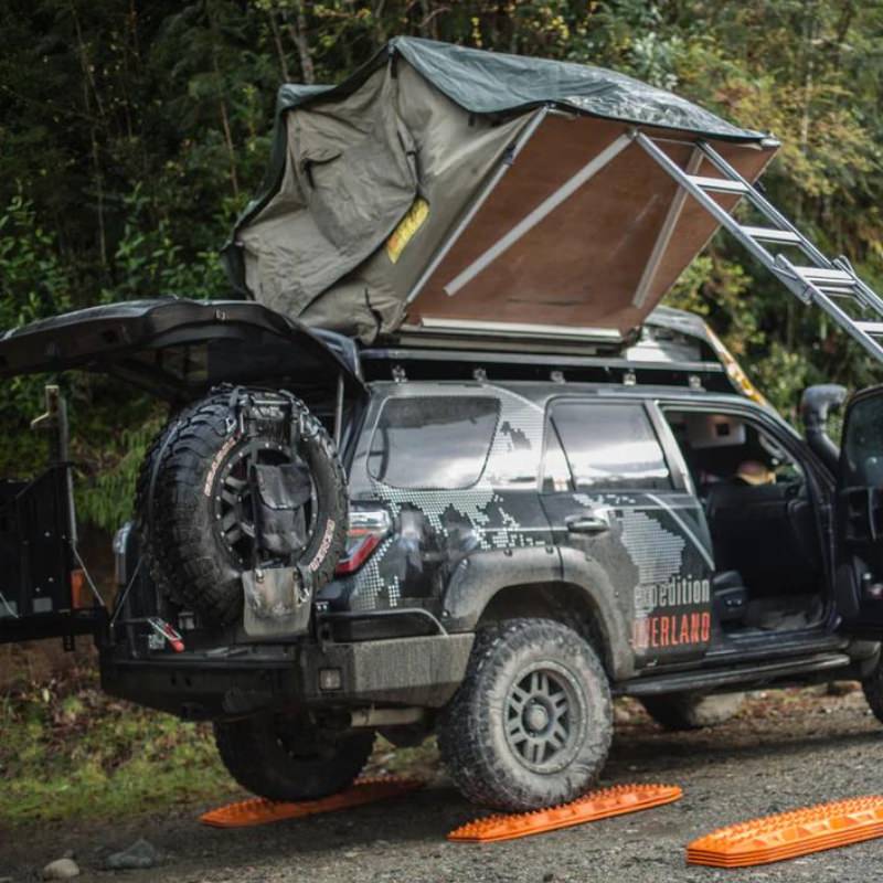 eezi-awn-series-3-soft-shell-roof-top-tent-olive-open-rear-corner-view-on-vehicle-with-person-in-nature-closing-tent