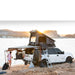 eezi-awn-stealth-hard-shell-roof-top-tent-open-rear-corner-view-on-ford-explorer-with-person-in-beach-camp