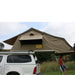 eezi-awn-xklusiv-soft-shell-roof-top-tent-beige-open-side-view-on-vehicle-with-person-and-extended-ladder-in-nature