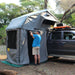 eezi-awn-xklusiv-soft-shell-roof-top-tent-gray-open-front-corner-view-on-vehicle-with-person-in-forest