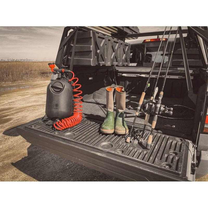 leitner-hydropod-carry-portable-shower-kit-front-view-on-truck-bed-with-boots-and-fishing-rods-in-nature
