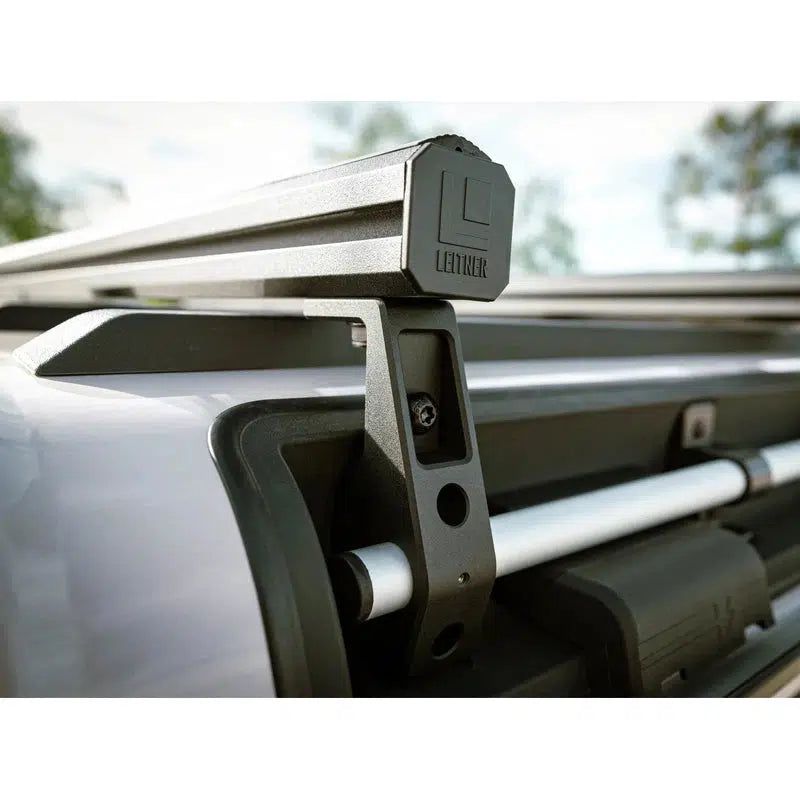 leitner-ineos-grenadier-2024-load-bar-kit-2-bars-close-up-view-on-vehicle-with-logo-and-mounting-hardware-in-nature