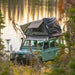 overland-vehicle-systems-bushveld-hard-shell-roof-top-tent-open-on-land-rover-defender-in-nature