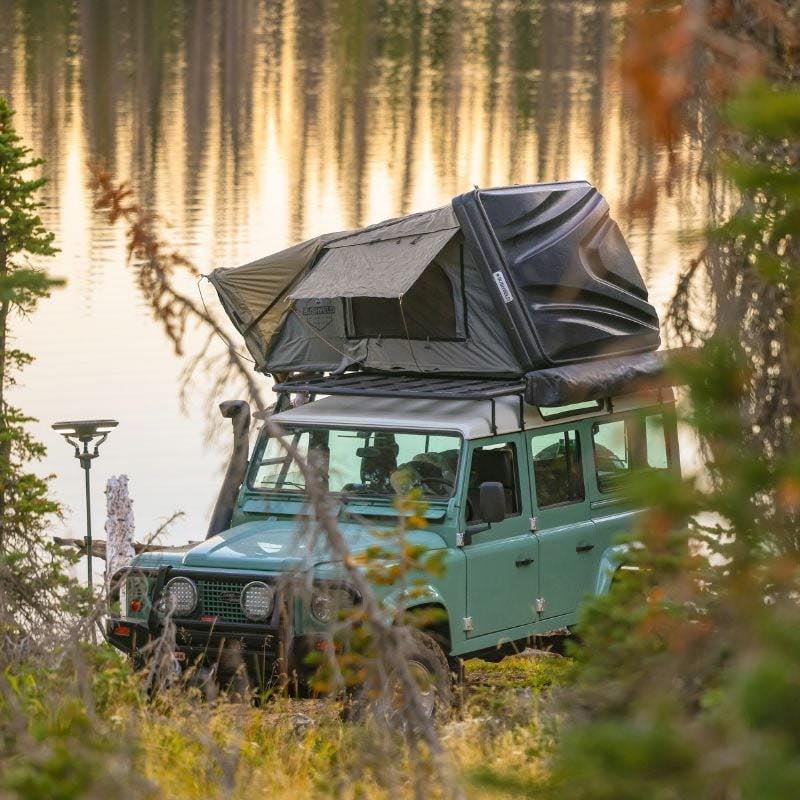 overland-vehicle-systems-bushveld-hard-shell-roof-top-tent-open-on-land-rover-defender-in-nature