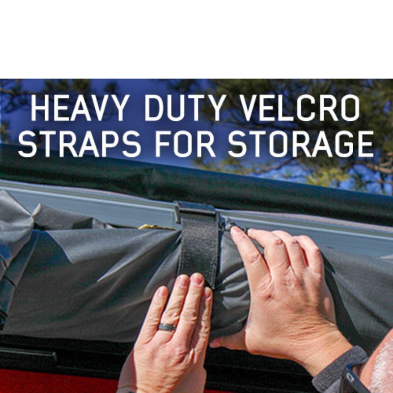 overland-vehicle-systems-nomadic-awning-4.5-ft-gray-open-close-up-view-with-hand-holding-velcro-strap-in-nature