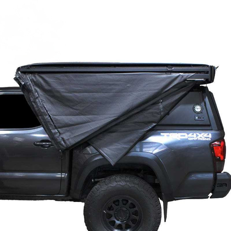 overland-vehicle-systems-xd-nomadic-270-degree-awning-black-closed-side-view-on-toyota-tacoma-with-truck-cap-on-white-background