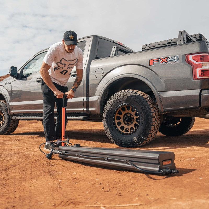 roam-7-gallon-water-tank-front-corner-view-with-person-pumping-on-terrain