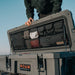roam-95l-lid-organizer-front-corner-view-on-rugged-case-with-person-in-nature