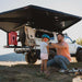 roam-arc-270-awning-passenger-side-open-interior-view-with-persons-in-nature