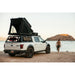 roam-desperado-hardshell-rooftop-tent-open-front-corner-view-on-vehicle-with-person-at-the-beach