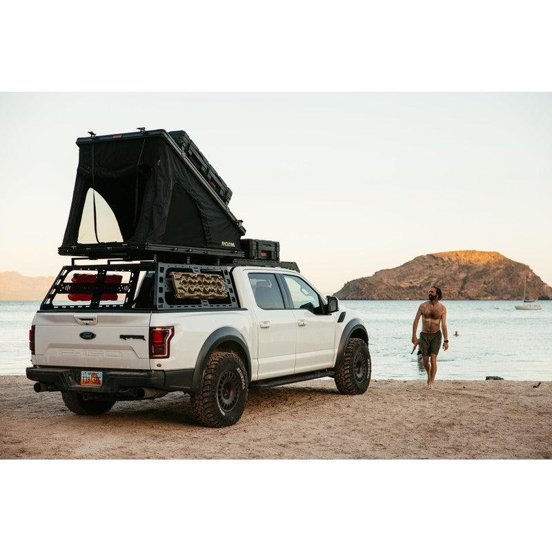 roam-desperado-hardshell-rooftop-tent-open-front-corner-view-on-vehicle-with-person-at-the-beach