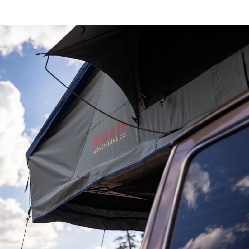 roam-vagabond-xl-rooftop-tent-slate-gray-navy-blue-open-close-up-view-with-brand-logo-in-nature