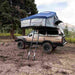roam-vagabond-xl-rooftop-tent-slate-gray-navy-blue-open-front-corner-view-on-toyota-land-cruiser-with-tie-down-points-in-nature