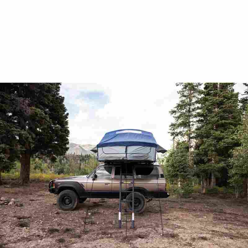 roam-vagabond-xl-rooftop-tent-slate-gray-navy-blue-open-front-view-on-toyota-land-cruiser-with-ladder-in-nature