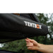 tentbox-cargo-side-awning-closed-close-up-view-on-vehicle-with-hand-holding-zipper-in-nature