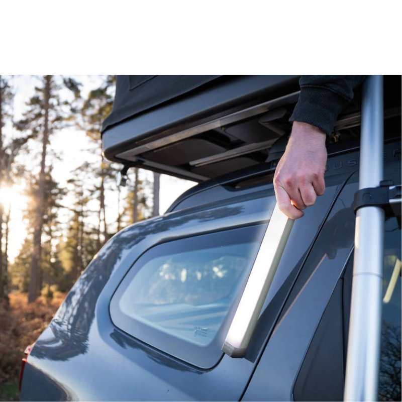 tentbox-classic-2-hard-shell-roof-top-tent-midnight-gray-open-close-up-view-on-vehicle-with-hand-holding-led-light-in-nature