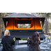 tentbox-universal-side-awning-closed-front-view-on-dacia-duster-with-persons-drawing-out-awning-canopy-in-nature