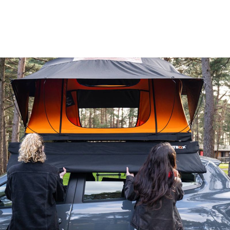 tentbox-universal-side-awning-closed-front-view-on-dacia-duster-with-persons-drawing-out-awning-canopy-in-nature