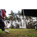 tentbox-universal-side-awning-open-close-up-view-with-person-hammering-the-peg-into-the-ground-in-nature